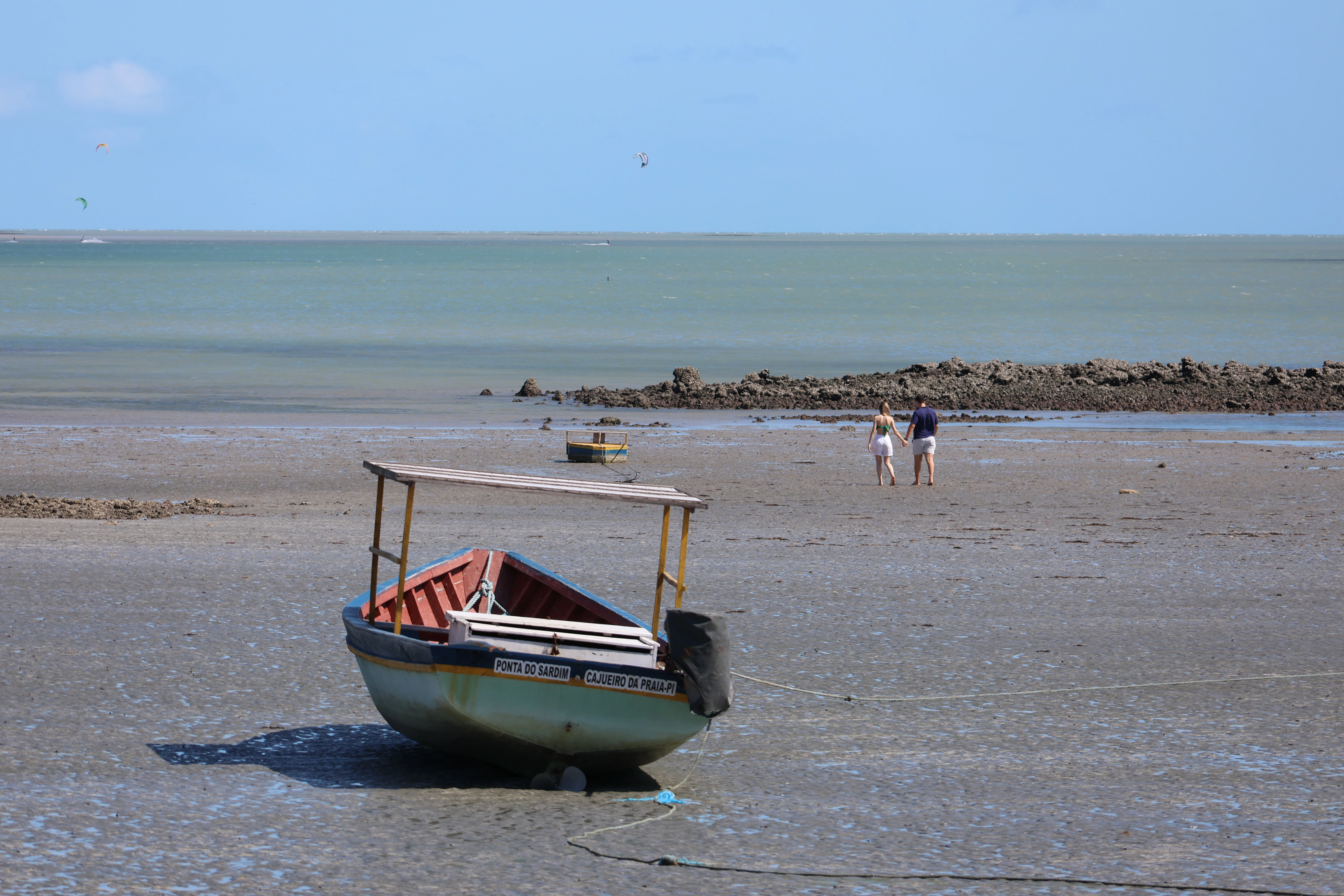 Praia com barco ancorado na areia e céu azul com nuvens